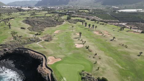 Drone-ascends-above-golf-course-on-rocky-ocean-cliffs-in-Tenerife-Spain