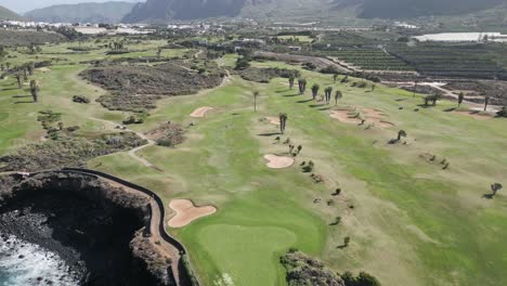 drone ascends above golf course on rocky ocean cliffs in tenerife spain