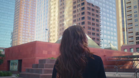 Unrecognizable-brunette-looking-on-skyscraper-back-view.-Lady-walk-city-street.