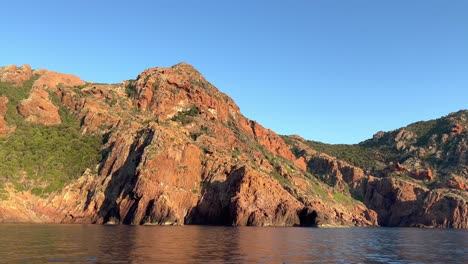 Panning-view-of-Scandola-French-peninsula-nature-reserve-in-summer-season-as-seen-from-moving-boat,-Corsica-island-in-France