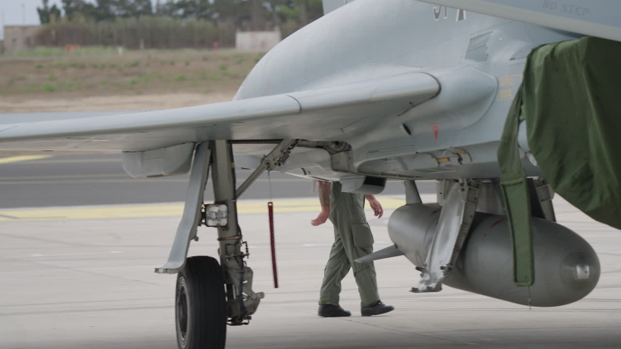 Miembro del personal de tierra militar inspecciona un caza en la plataforma