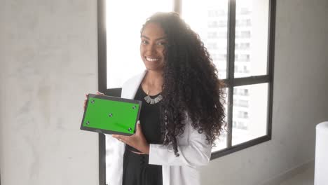 beautiful-black-woman-holding-tablet-green-background-horizontal-smiling