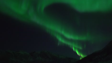 la aurora boreal filmada en tiempo real sobre el paisaje montañoso en la isla kvaløya cerca de tromsø en el norte de noruega