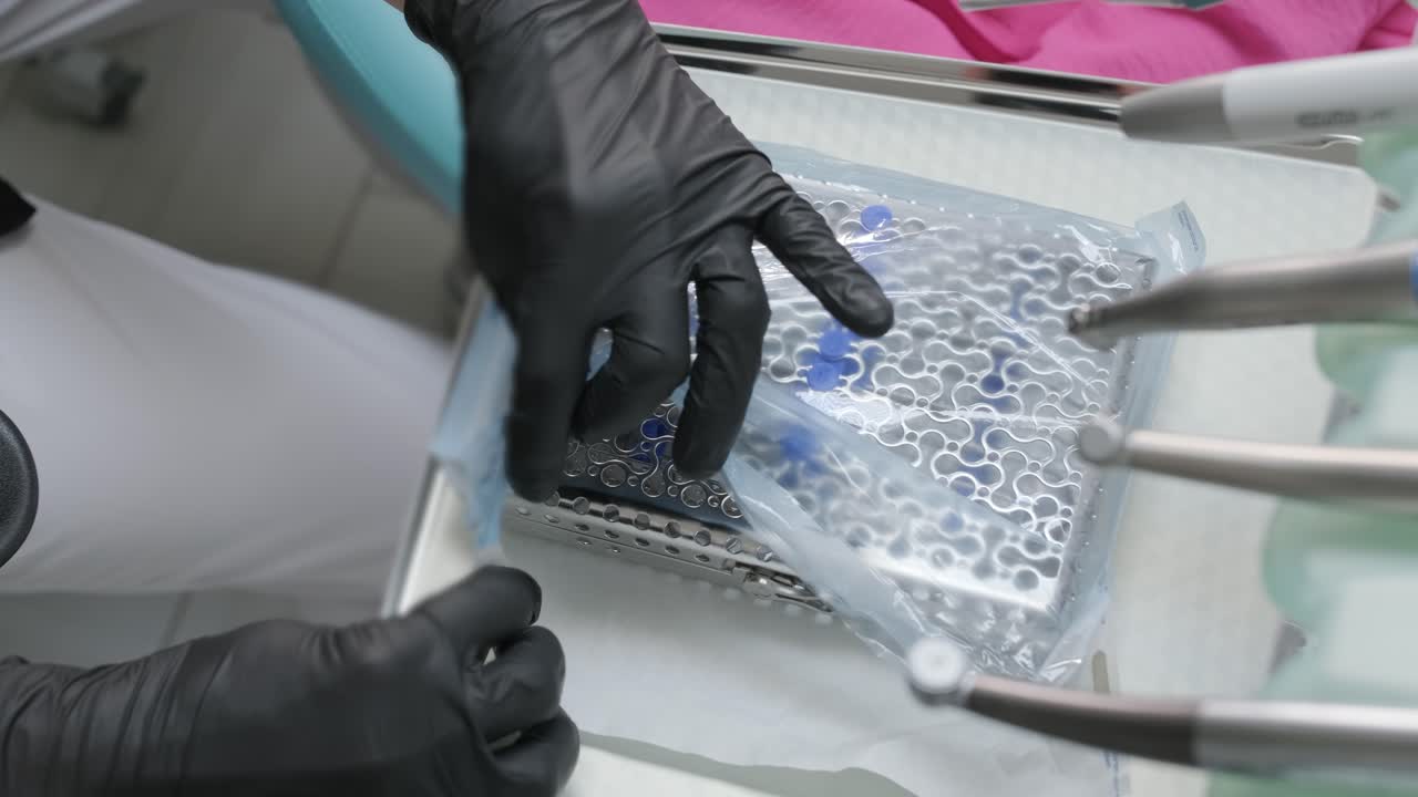 las manos abren una caja con un instrumento médico. caja de esterilización. esterilización de instrumentos. herramientas dentales. procedimiento de sterilización. autoclave de vapor.