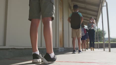 Gruppe-Von-Kindern,-Die-Gesichtsmasken-Tragen-Und-In-Der-Schule-Soziale-Distanz-Wahren