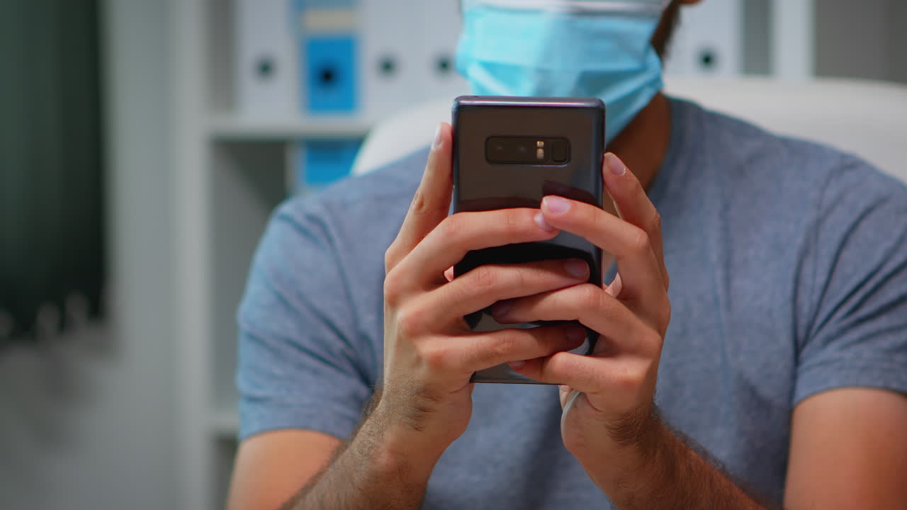 hombre con máscara escribiendo en el teléfono