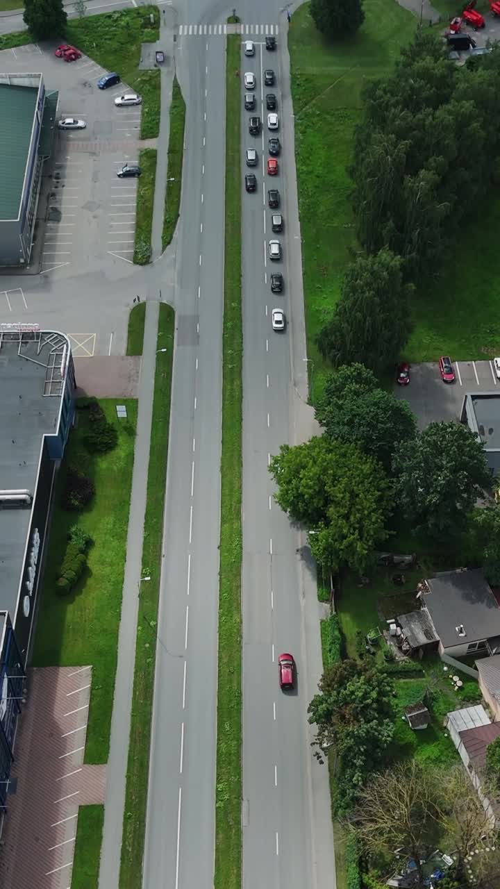 Bird’s-eye vertical shot captures busy traffic moving along a street in Darzciems