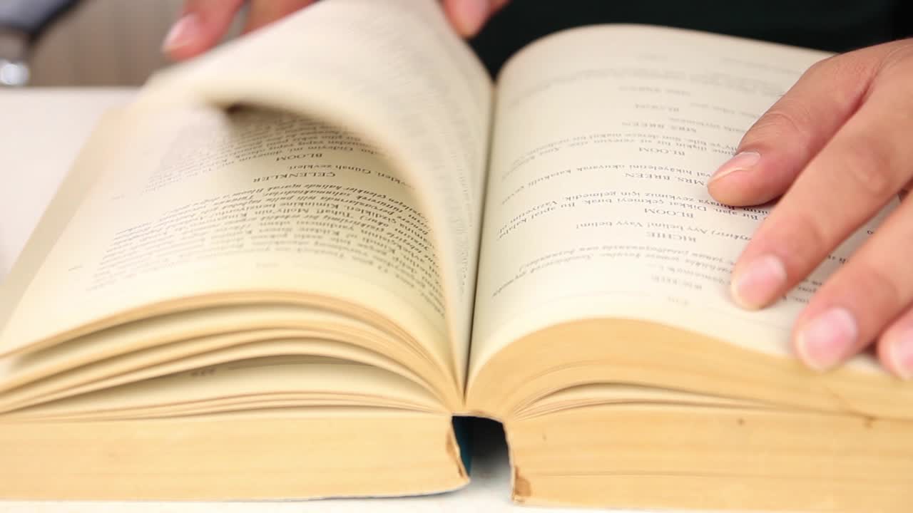 estudiante de sexo masculino leyendo un libro sentado entre pilas de libros