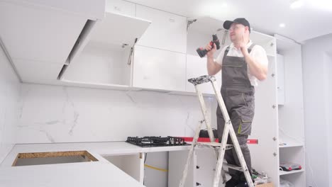 funny and cheerful kitchen furniture installer dancing on a ladder funny and cheerful kitchen furniture installer dancing on a ladder happy young worker at work