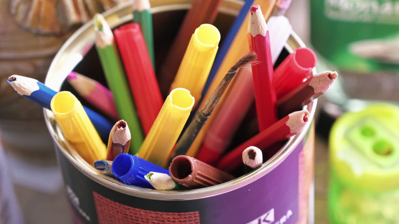 A cup with multiple colored pencils and markers