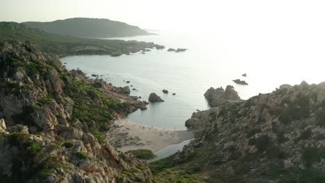 revealing aerial shot of exotic small beach between mountains on italian sardinia island