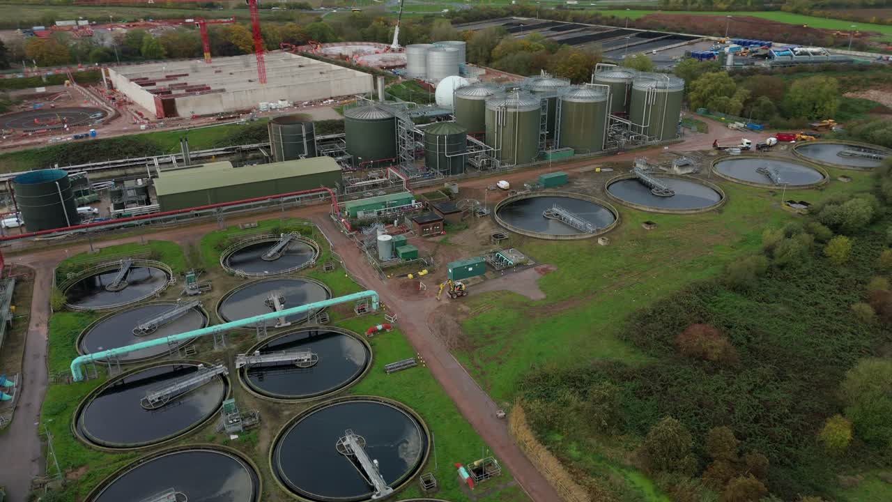 Top down aerial drone establishing shot of Severn Trent sewage facility with settling pools, circular clarifiers, silos and tanks in Leicester UK