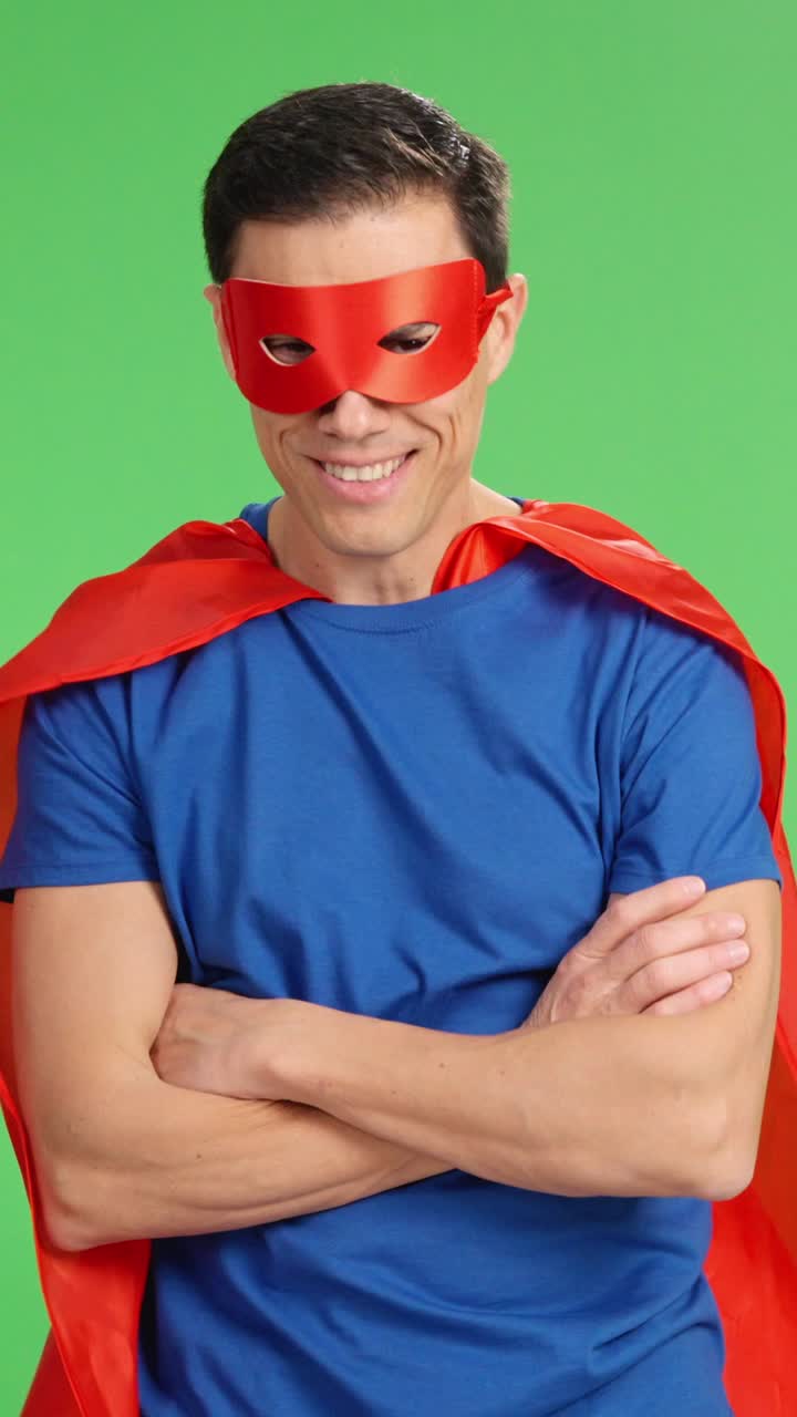 Superhero posing with crossed arms and showing determination on green screen