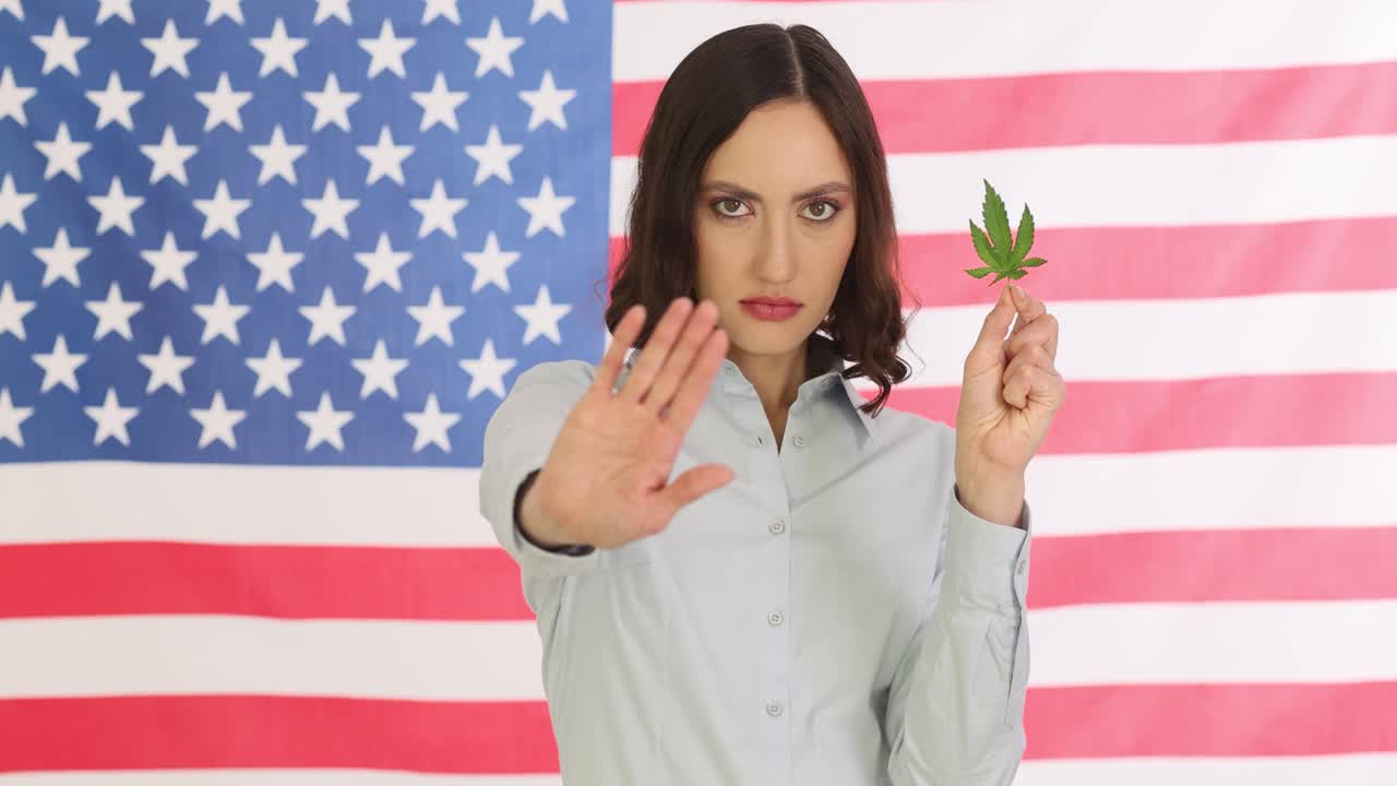 Businesswoman holds marijuana leaf and signals stop with hand