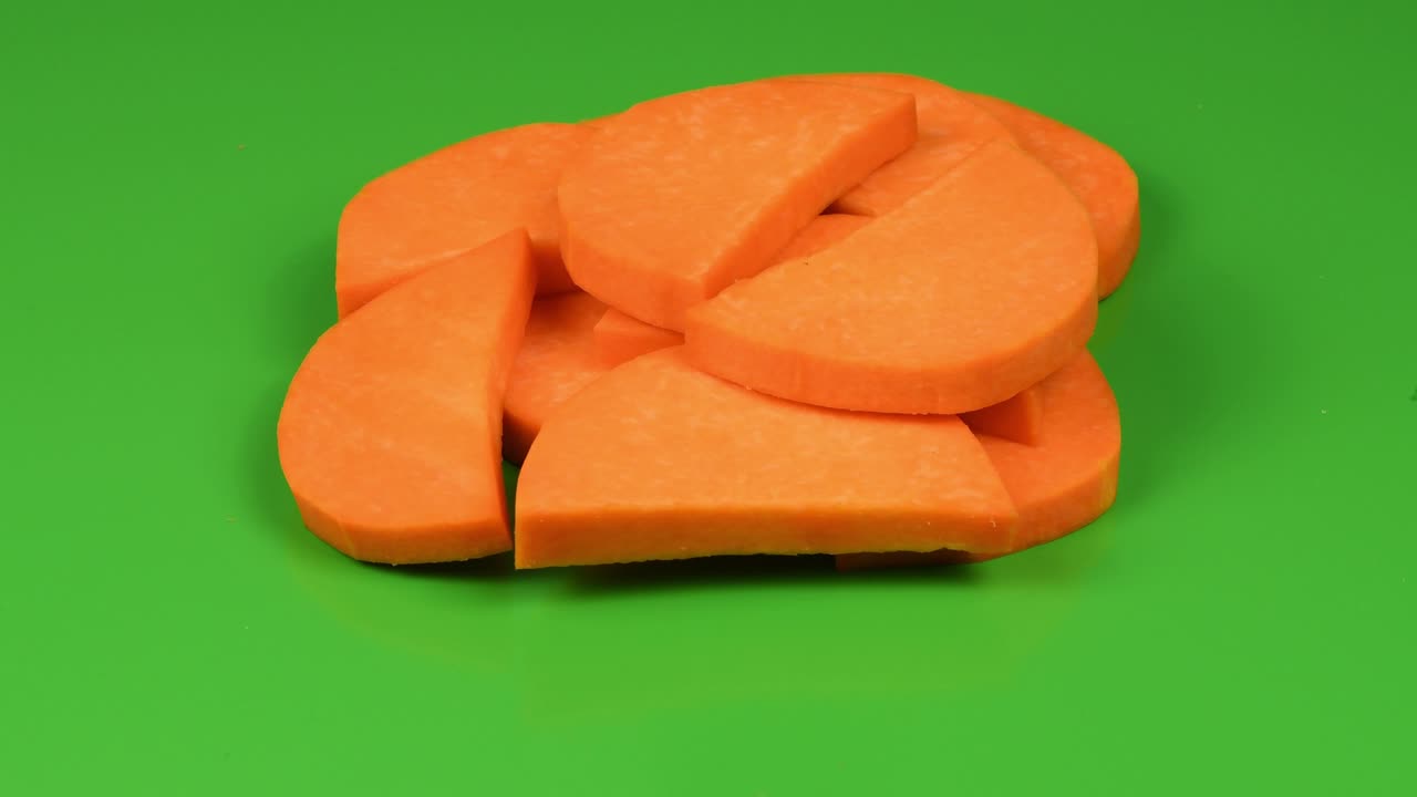 calabaza cortada en rodajas (cucurbita moschata, calabaza de nuez o grama de guitarra) aislada en verde. vista lateral. movimiento en bucle. rotación 360.