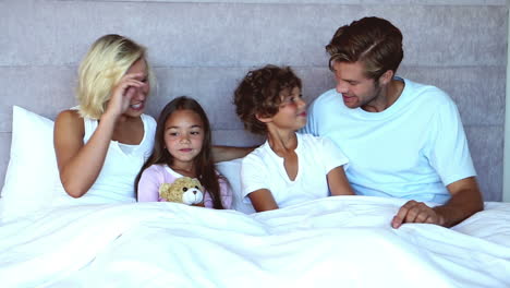 family sitting in bed