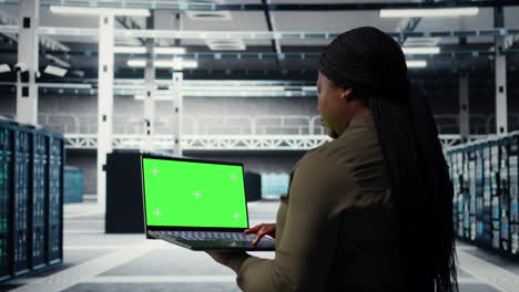 engineer at work using green screen laptop in data center to check hardware
