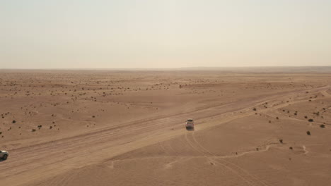 다른 4x4 드라이브가 지나가는 동안 비포장 도로에서 빠져나오는 4x4 자동차 주변을 비행하는 드론