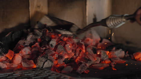 rastrillando carbón en una parrilla de leña