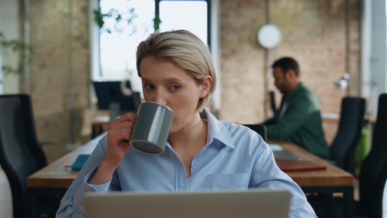 Mulher de negócios sobrecarregada de trabalho sentada em um escritório de trabalho olhando para a tela do laptop de perto