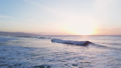 people swim and surf at ocean with waves during beautiful sunset in north shore, oahu, hawaii