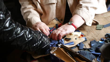 Aprender-A-Hacer-Manualidades-Con-Restos-De-Tela-Para-Crear-Una-Alfombra-De-Trapo-Sobre-Una-Mesa-De-Madera,-Lo-Que-Representa-Habilidades-En-Artes-Textiles