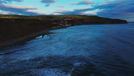 Establishing-Drone-Shot-of-Robin-Hood's-Bay-and-Coastline-at-Sunrise