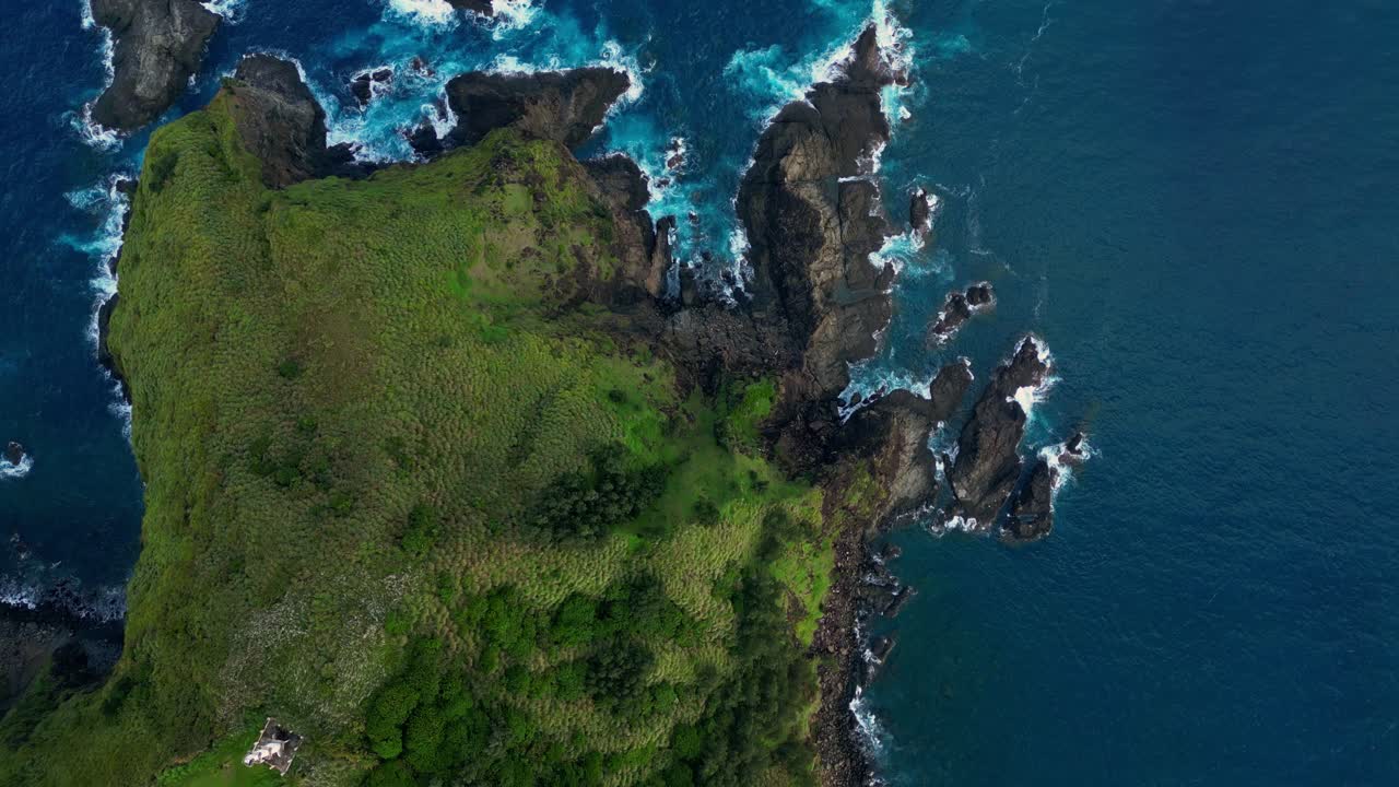 Rotating top‑down aerial of the Suah Rock Formation in Dingalan, Aurora, circling the rugged hill cliffs draped in lush greenery as waves crash against the dramatic shoreline