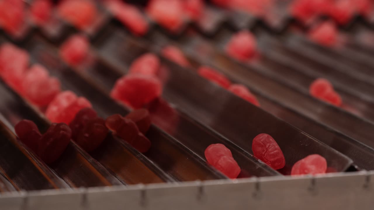 Red gummy vitamins sliding down grid - close-up shot
