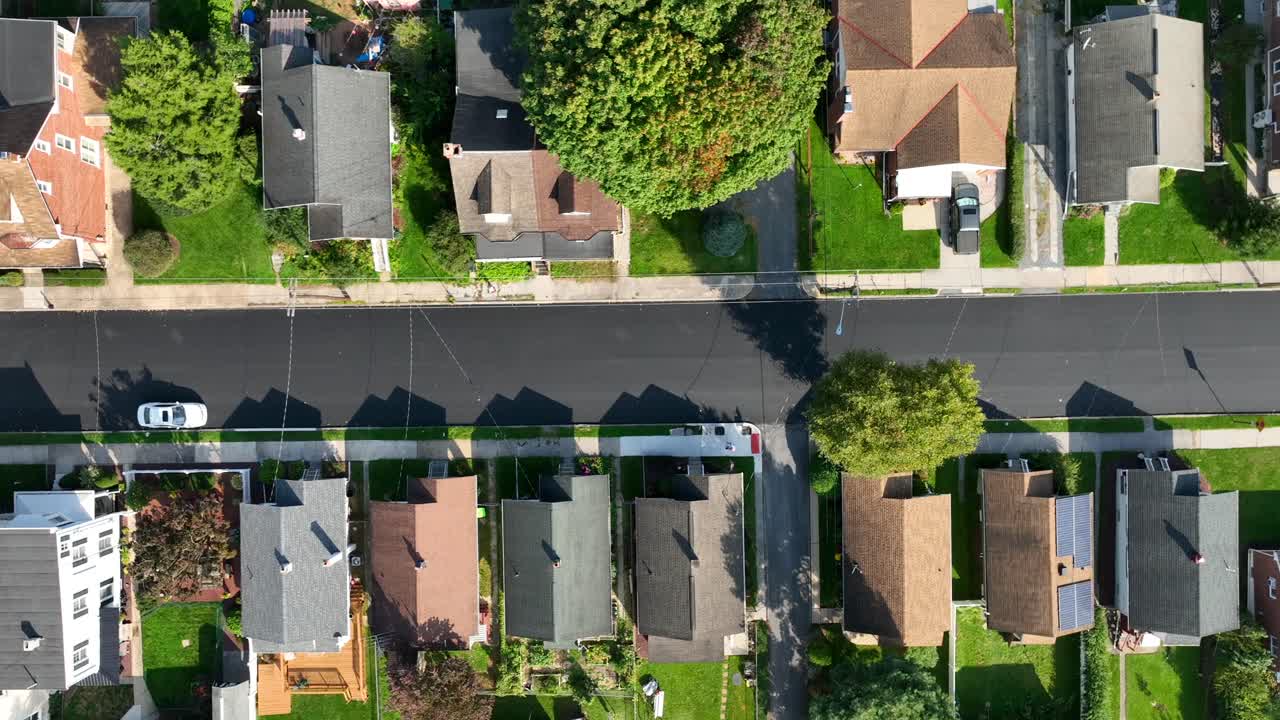 vista de pájaro de una calle suburbana con casas alineadas y sombras de árboles