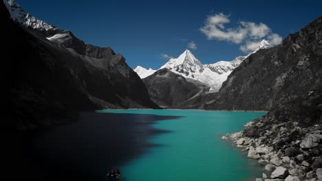 drone volando sobre un lago azul montaña nevada de paramount pictures en laguna paron, huaraz, perú