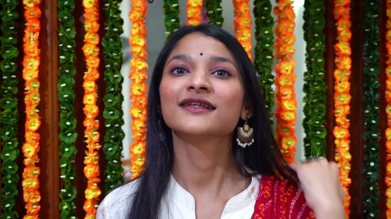 Bella ragazza indiana che si toglie gli occhiali e guarda la macchina fotografica - Ragazza indiana con ghirlande colorate sullo sfondo ad Agra, India - Piano medio