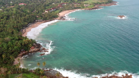slow drone flight along coastline highlighting beaches, palm trees, and turquoise waters in sri lanka.