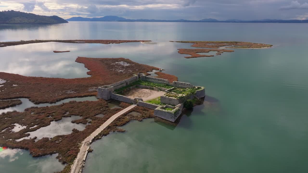 Pohled dronem na kamennou pevnost odrážející se na klidné hladině jezera