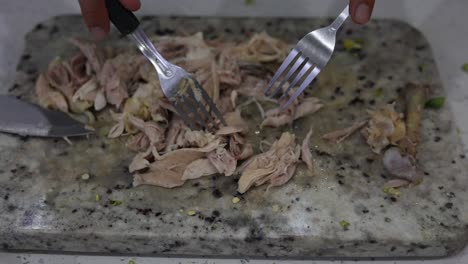 cutting-chicken-with-a-fork-on-a-chopping-board-in-the-kitchen