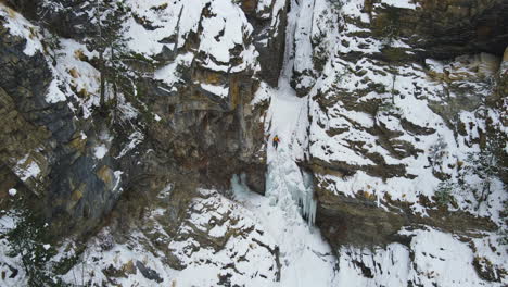 La-Toma-De-Un-Dron-Revela-El-Paisaje-Del-Circuito-De-Annapurna-En-Nepal,-Un-Excursionista-Sube-A-Una-Cascada-Congelada-En-Manang-Con-Clima-Nevado,-Una-Experiencia-De-Turismo-Aventurero-4k