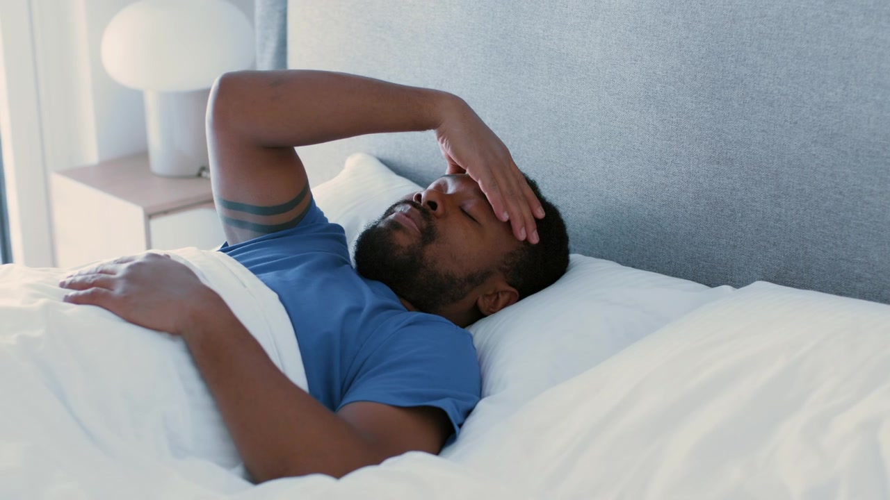 Man Waking Up With a Headache in Bed