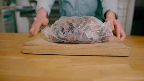 View-of-a-man-placing-a-frozen-steak-loft-in-flank-on-the-table