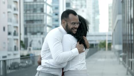 smiling african american man in eyeglasses embracing friend