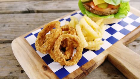 Hamburger,-onion-ring-and-french-fries-on-chopping-board