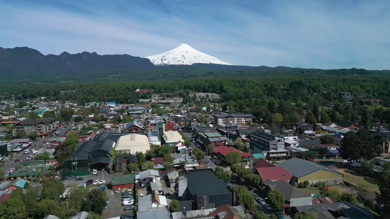 Panoramic drone view of downtown Pucon with the Villarrica volcano towering in the background