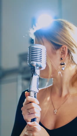 attractive woman singing into a mic. professional singer standing at the microphone and performing a live music. slow motion. vertical video