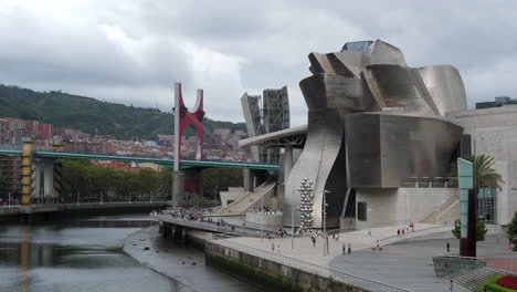 people walking outside the guggenheim museum bilbao with puente de la salve in the background in bilbao, basque, spain