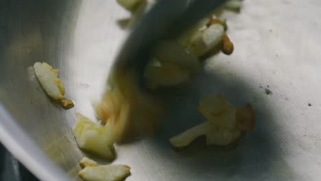 stirring golden brown pieces of garlic in frying pan