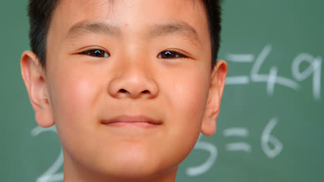 close-up of asian schoolboy standing against chalkboard in a classroom at school 4k