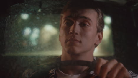 man driving vintage taxi cab at night with raindrops on windshield
