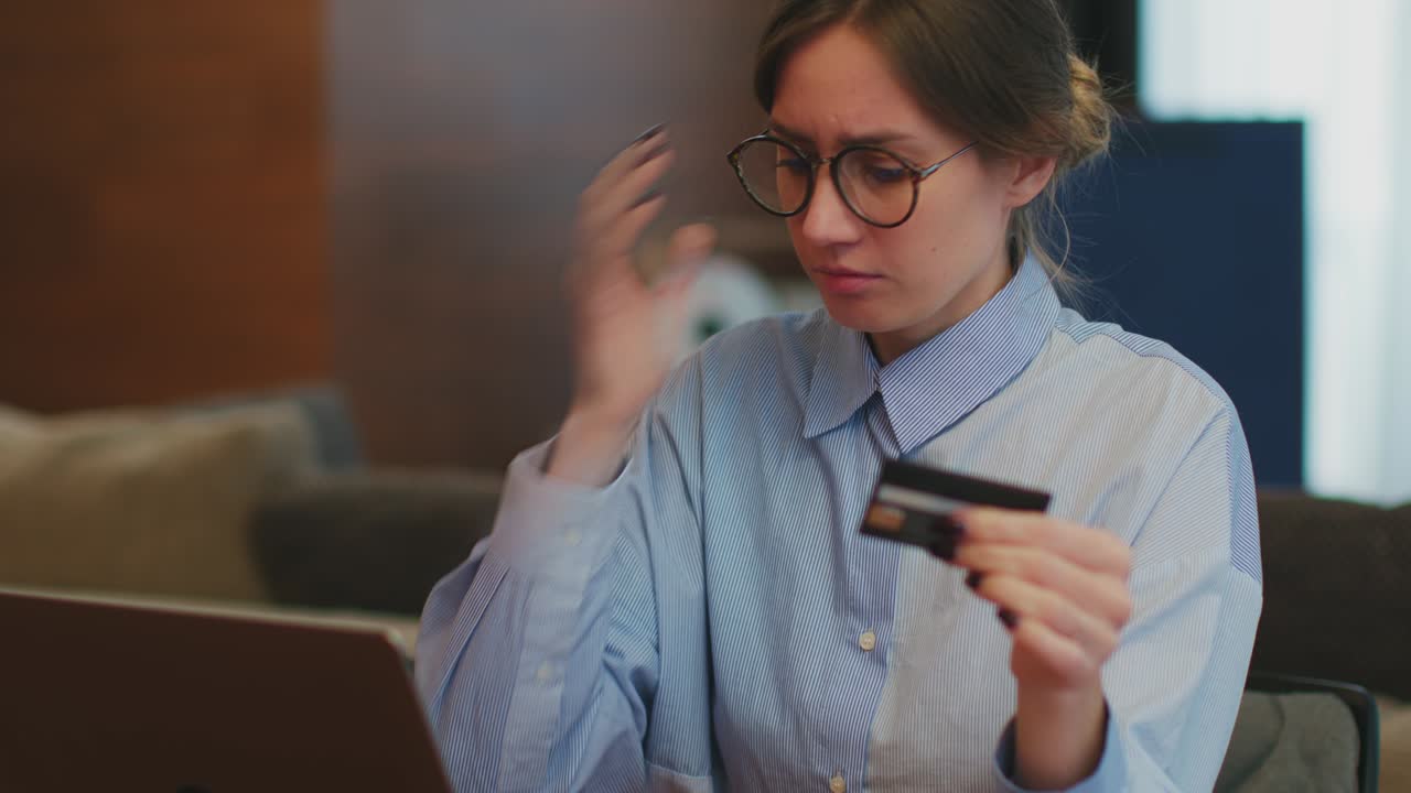 empleada desconcertada con gafas hace el trabajo sosteniendo una tarjeta bancaria escribiendo información en una computadora portátil. banca en línea, comercio electrónico