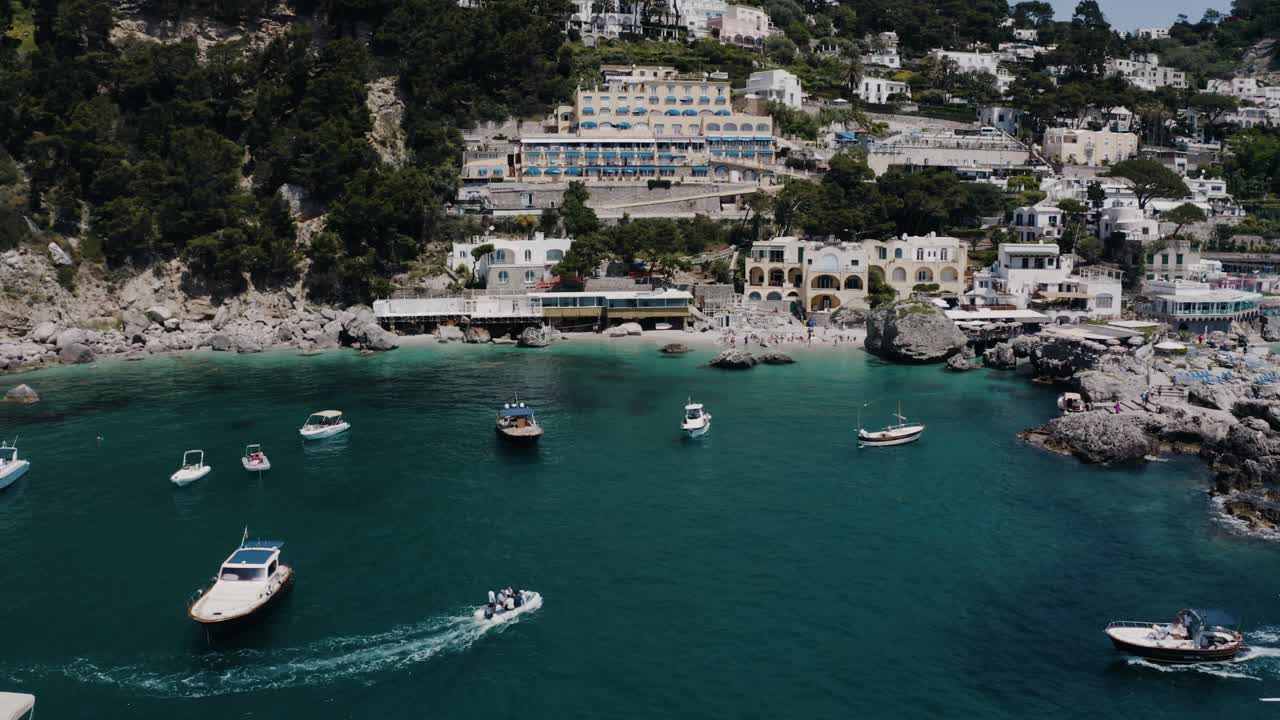 Drone shot of expensive boats floating along Italy's resort-filled shore
