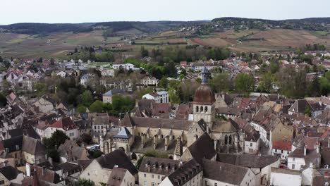 a historic french town sits humbly at the foot of hills covered in vineyards