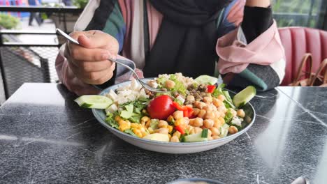 woman eating a healthy mixed salad bowl at a cafe